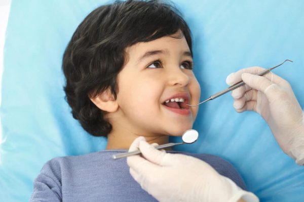Little baby girl sitting at dental chair with open mouth during oral check up while doctor. Visiting dentist office. Medicine concept.